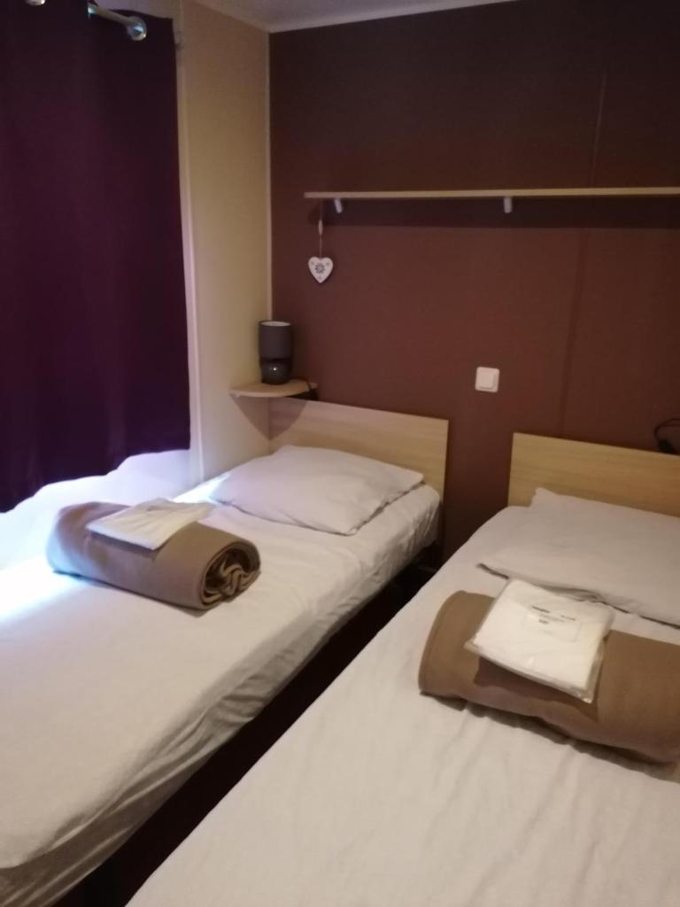 deux lits dans une chambre d'hôtel avec des serviettes dessus dans l'établissement MOBILHOME COSY SPACIEUX 42m2, CLIMATISE, TV & LL, 3 chambres, à Vic-la-Gardiole