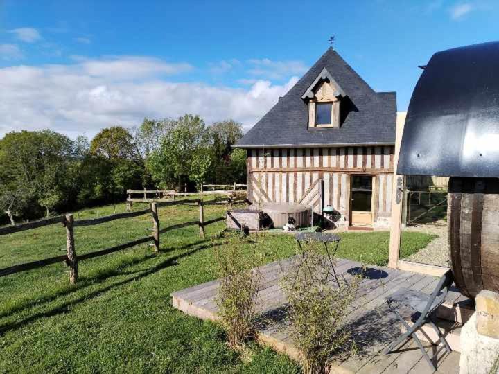 une grande maison avec une clôture et un champ dans l'établissement Tonneaux normands insolites, à Le Mesnil-Germain