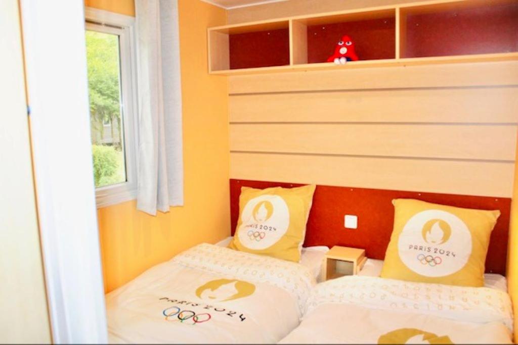 une petite chambre avec deux lits avec des oreillers olympiques dans l'établissement Mobil Home Cosy, à Saint-Chéron