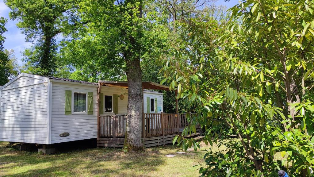 une petite cabine blanche avec un arbre dans la cour dans l'établissement Mobil Home Cosy, à Saint-Chéron