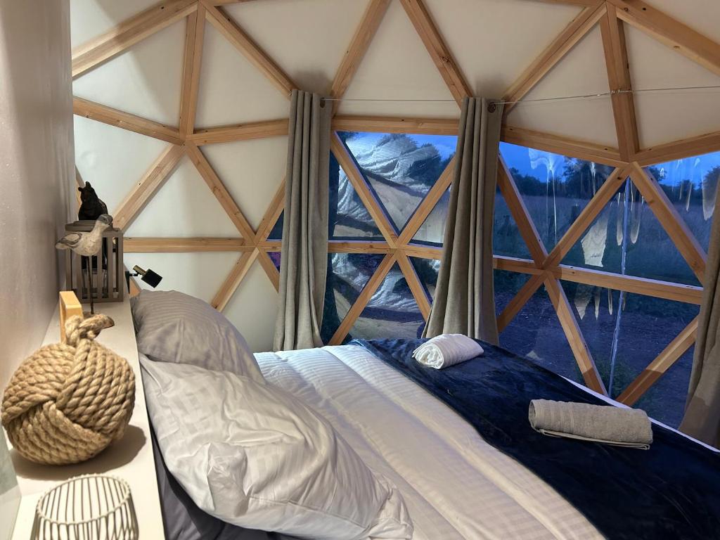 un lit dans une chambre avec une grande fenêtre dans l'établissement Dôme géodésique - Baie de Somme, à Favières 8 autres photos