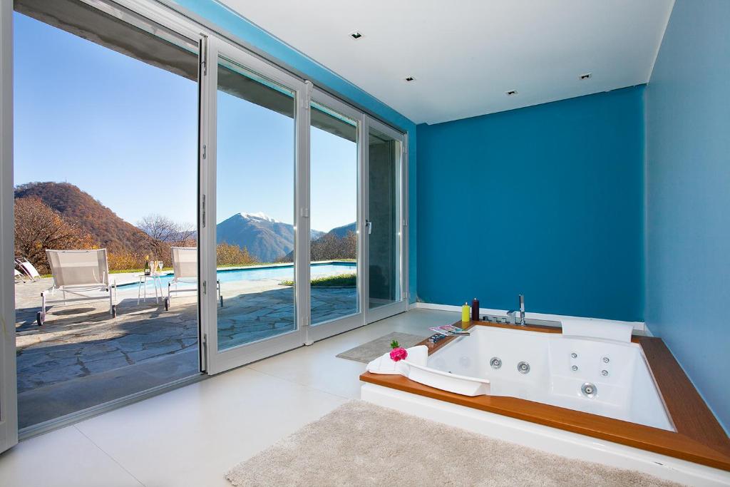La salle de bains bleue est pourvue d'une baignoire et d'une grande fenêtre. dans l'établissement Villa La Betulla, à Cerano d'Intelvi
