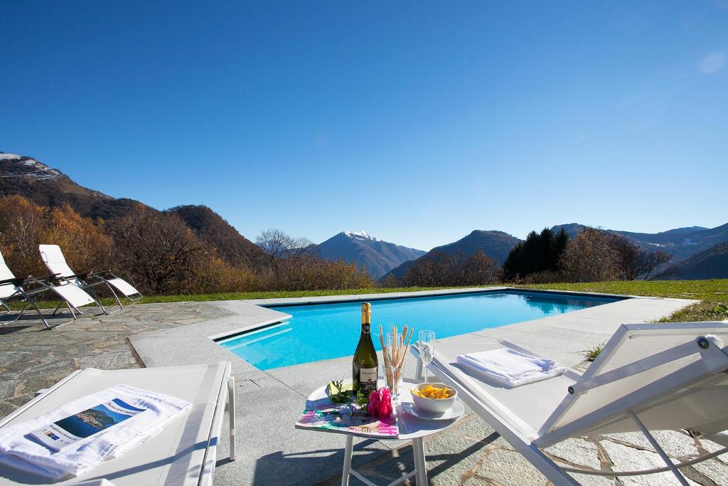 - une table avec une bouteille de vin à côté de la piscine dans l'établissement Villa La Betulla, à Cerano d'Intelvi