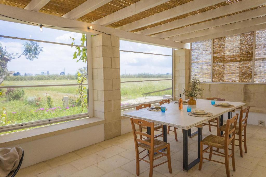 une salle à manger avec une table et une grande fenêtre dans l'établissement Villa La Reimunda, à Otrante