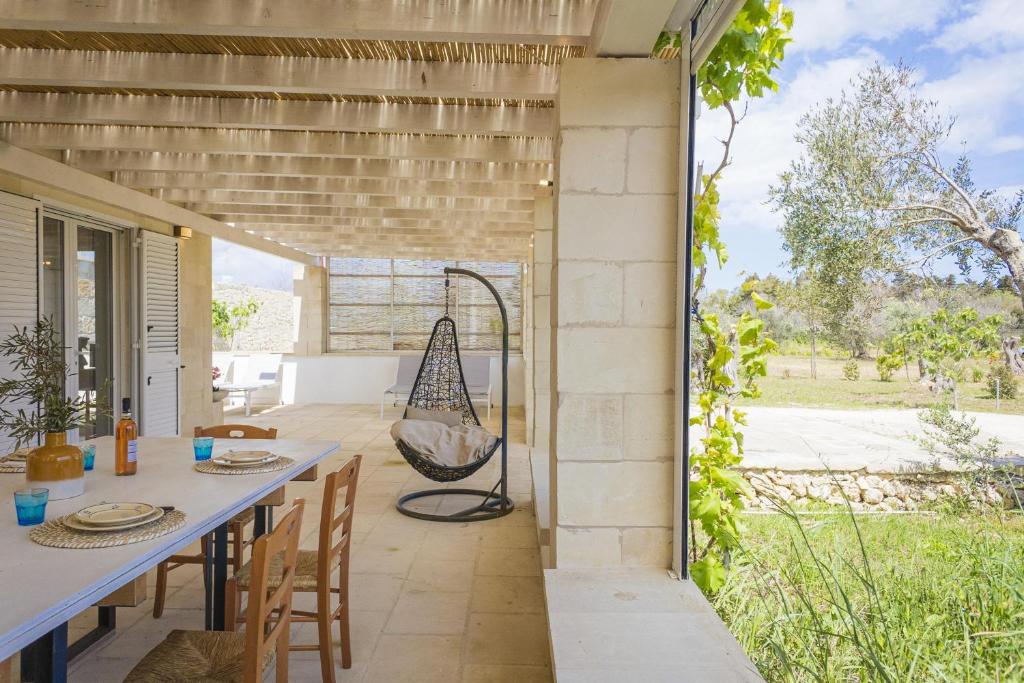 un patio extérieur avec une table, des chaises et une balançoire dans l'établissement Villa La Reimunda, à Otrante