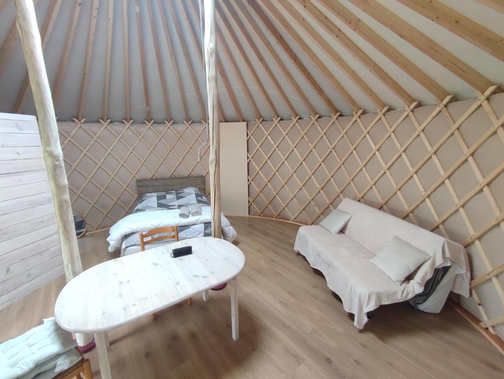 - une chambre avec 2 lits et une table dans une yourte dans l'établissement Chaleureuse yourte a la campagne, à Mourens