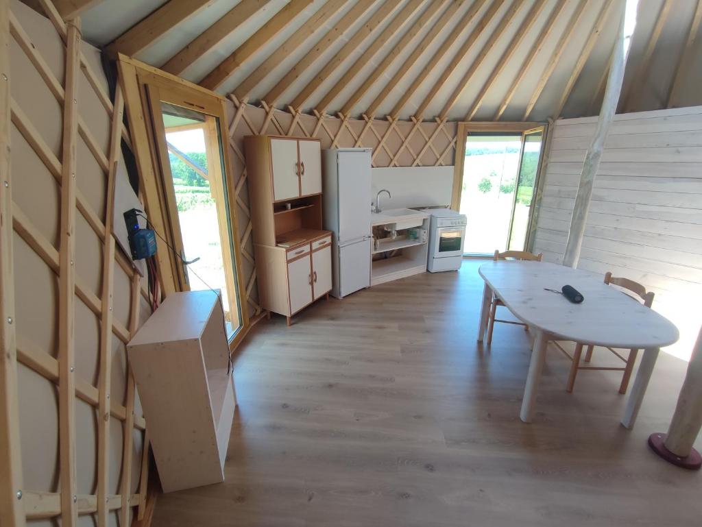 une chambre avec une table et une cuisine dans une maison dans l'établissement Chaleureuse yourte a la campagne, à Mourens
