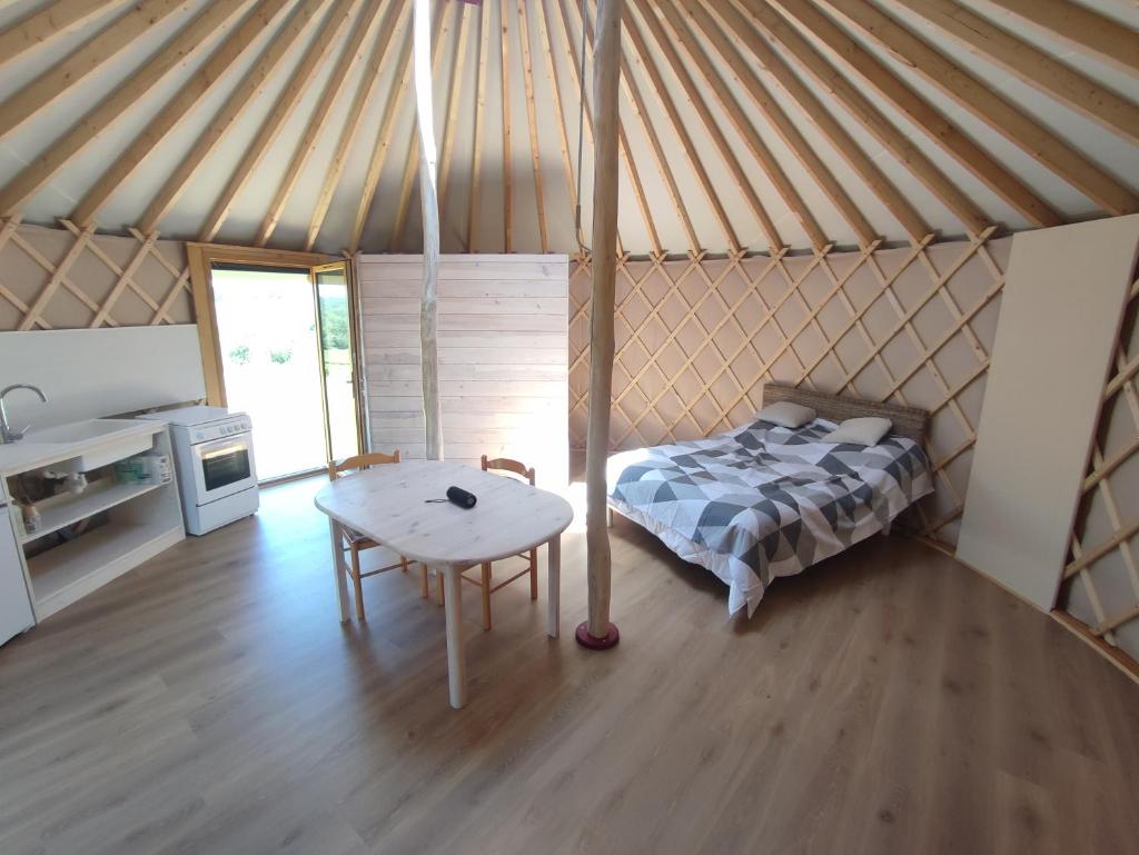 - une chambre avec un lit et une table dans une yourte dans l'établissement Chaleureuse yourte a la campagne, à Mourens