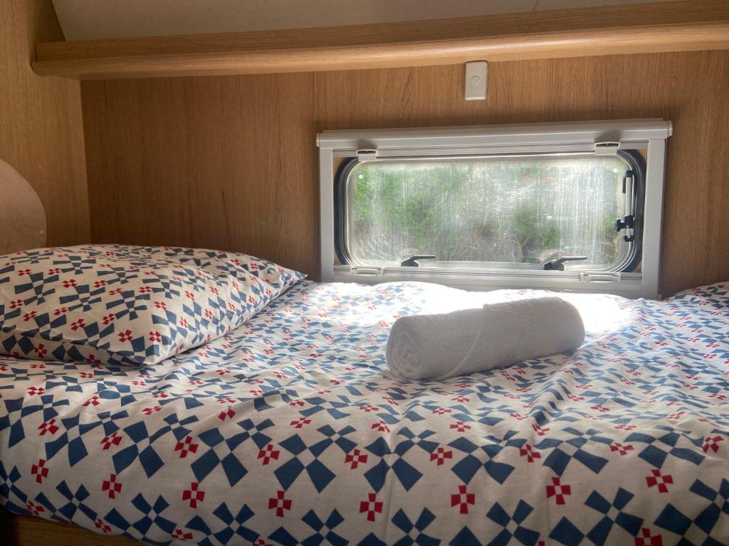 une chambre avec un lit avec un oreiller et une fenêtre dans l'établissement Camping-car au Charme de la Forêt Circuit des 25 Bosses, à Le Vaudoué