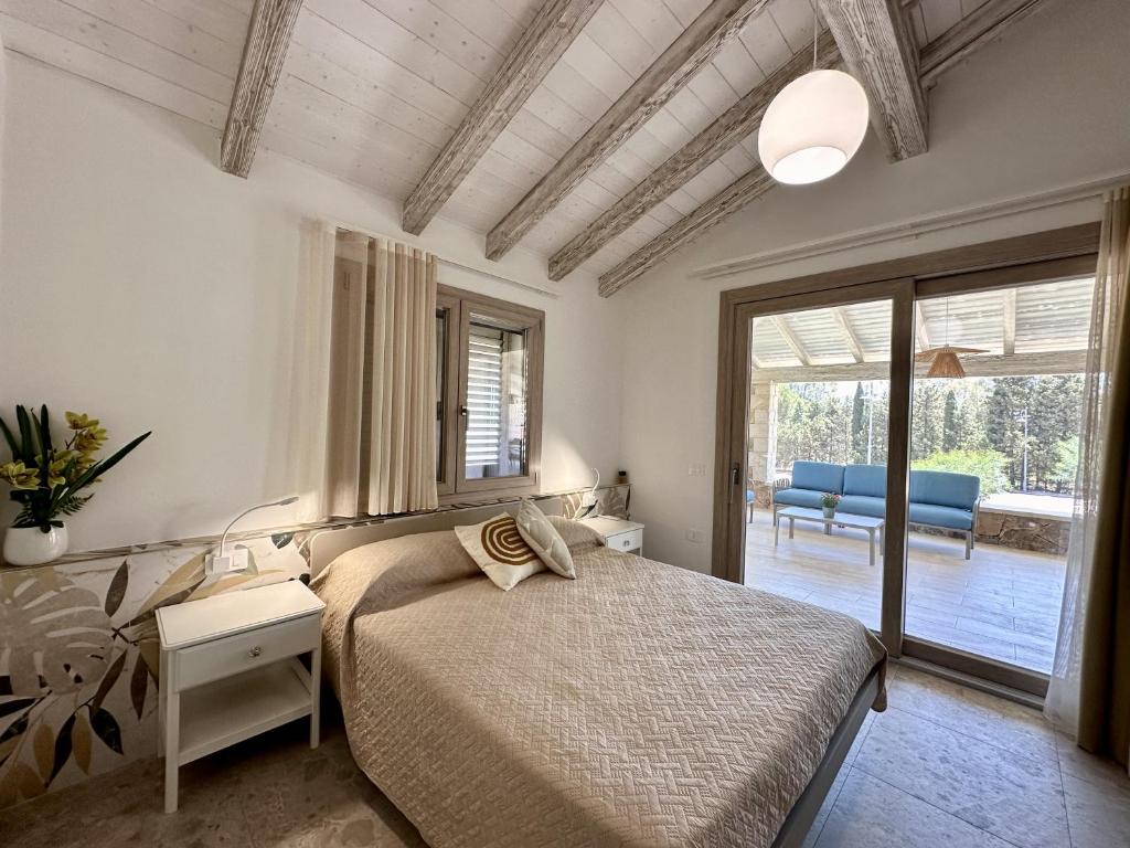 une chambre avec un lit et une porte coulissante en verre dans l'établissement Villa Smeraldo Castiadas, à Castiadas