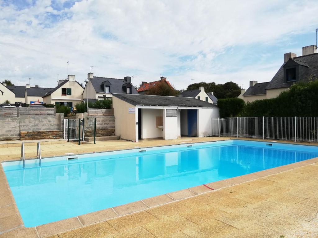 une grande piscine bleue avec une maison en arrière-plan dans l'établissement AR VAKANSOU - proche des plages et GR 34, à Clohars-Carnoët