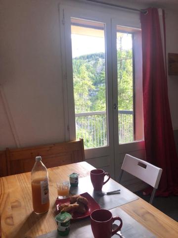 une table avec une assiette de nourriture et une fenêtre dans l'établissement joli studio montagne au pied des pistes, à Allos