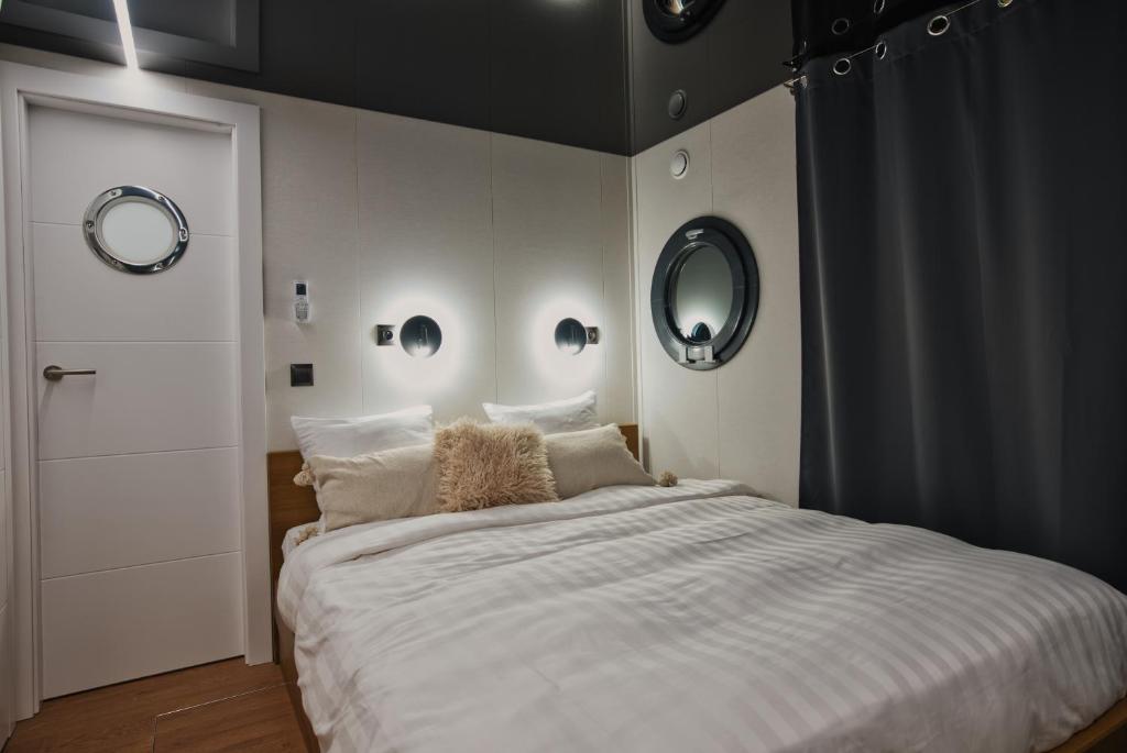 - une chambre avec un grand lit blanc et deux miroirs dans l'établissement Houseboat by Noma, à Saint-Étienne
