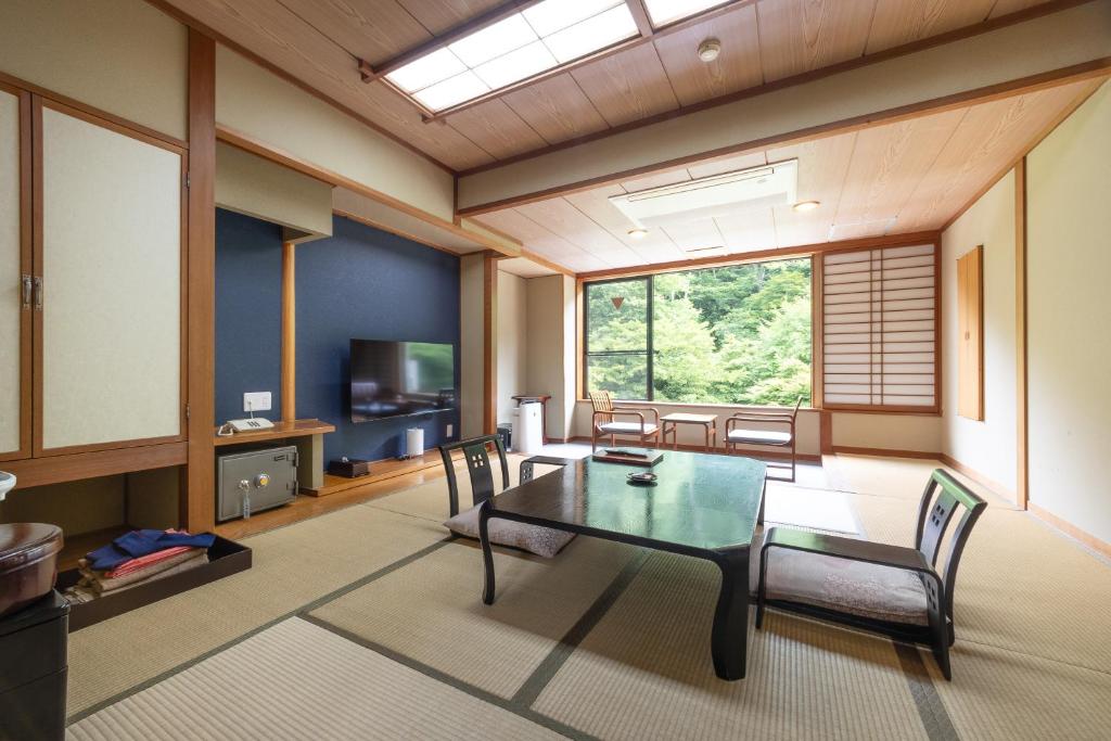 un salon avec une table en verre et des chaises dans l'établissement 式部のやかた井筒屋, à Shirakawa-gō