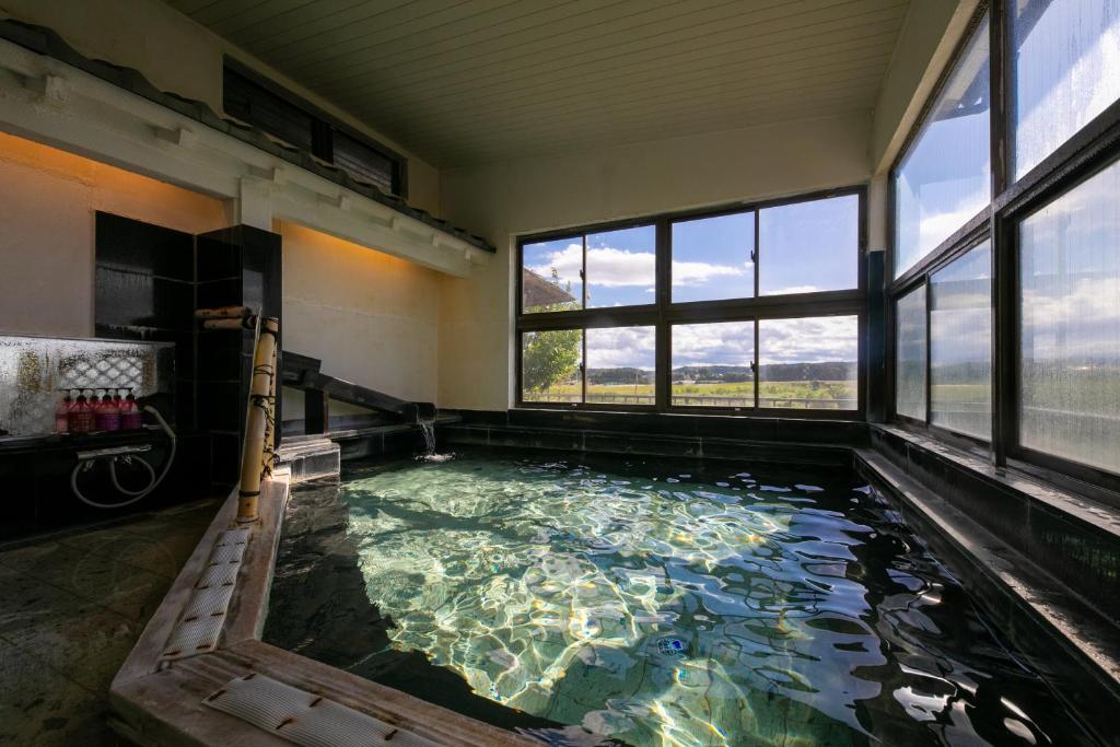 - une grande piscine d'eau dans une chambre avec fenêtres dans l'établissement Isamikan, à Nakagawa