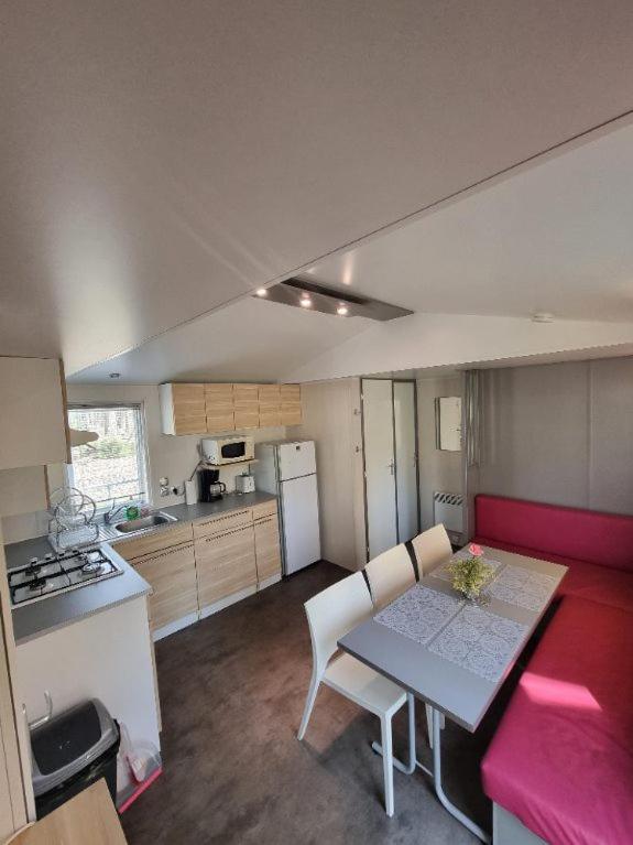Il dispose d'une cuisine avec une table et des chaises. dans l'établissement Ile de France, mobil-home cosy au coeur d' une forêt avec piscine, à Saint-Chéron