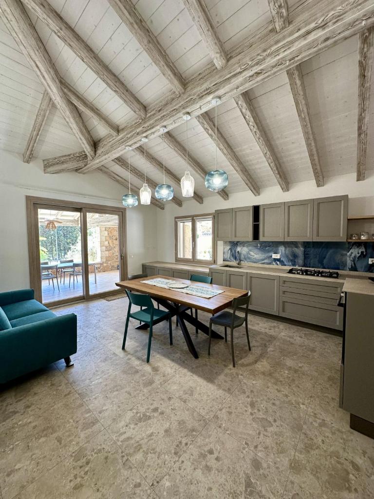 une grande cuisine avec une table en bois et des chaises vertes dans l'établissement Villa Smeraldo Castiadas, à Castiadas