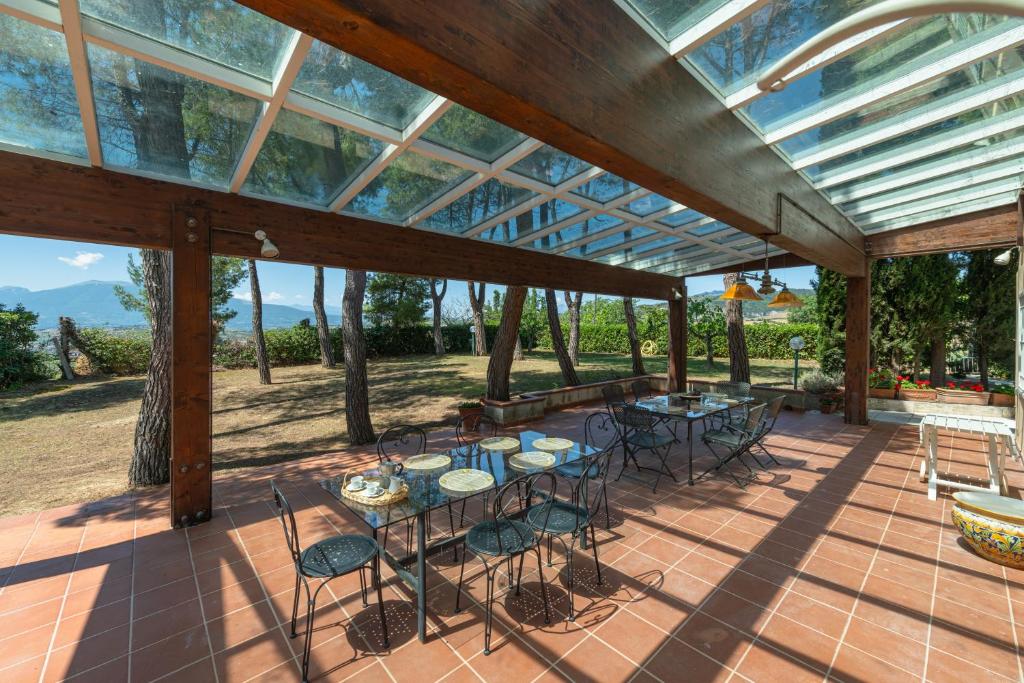 un patio avec des tables et des chaises sous un toit en verre dans l'établissement Villa Stipa with pool by Quokka 360 - Close to Riviera delle Palme, à Offida