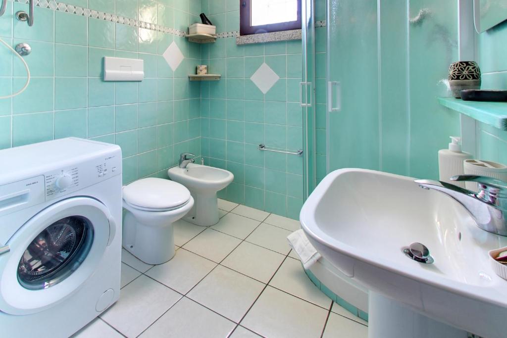 une salle de bains avec lave-linge et lavabo dans l'établissement Residence Oasi Anfiteatro, à Porto Ottiolu