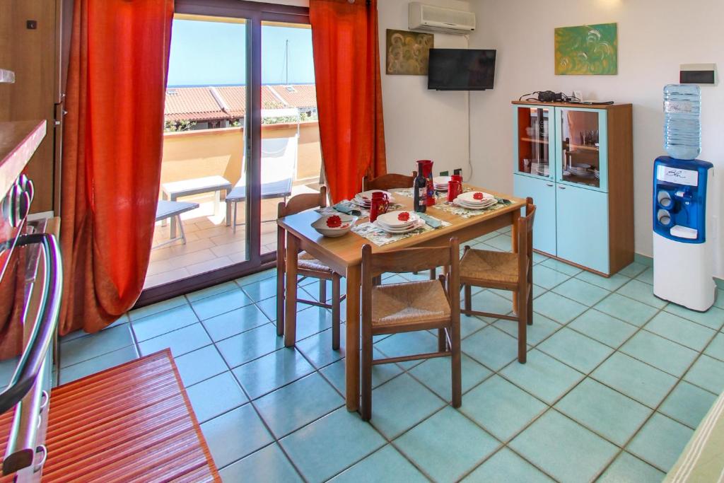 une salle à manger avec une table et une cuisine avec vue dans l'établissement Residence Oasi Anfiteatro, à Porto Ottiolu