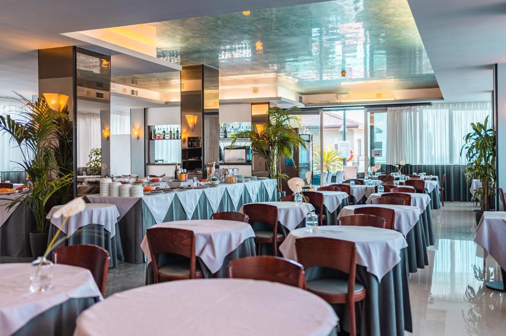 un restaurant avec tables et chaises et nappes blanches dans l'établissement Hotel Europa, à Lido di Jesolo