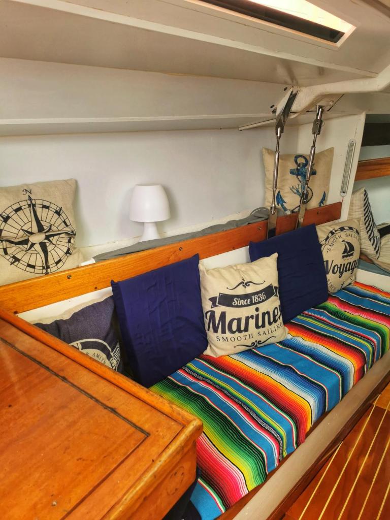 un lit sur un bateau avec des couvertures et des oreillers colorés dans l'établissement seuls à bord dans le golfe hebergement atypique, à Porto-Vecchio 4 autres photos
