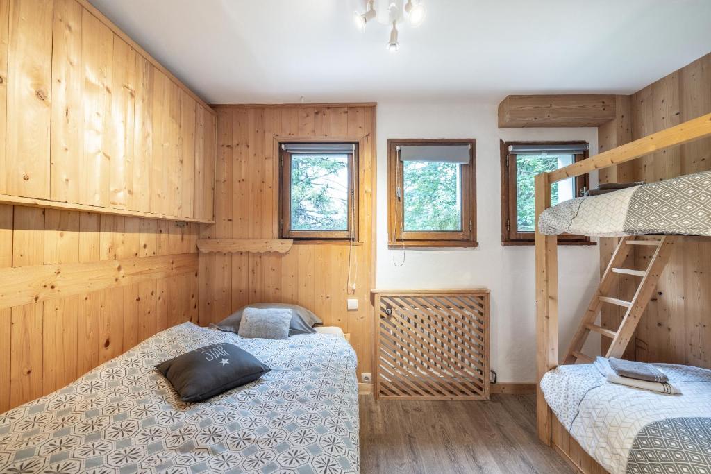 - 2 lits dans une chambre dotée de murs en bois et de fenêtres dans l'établissement Le chalet d Anita, à Megève