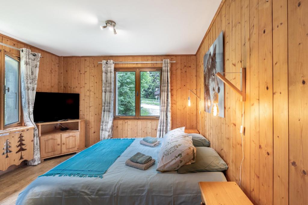 - une chambre dotée de murs en bois et d'un lit avec une télévision dans l'établissement Le chalet d Anita, à Megève