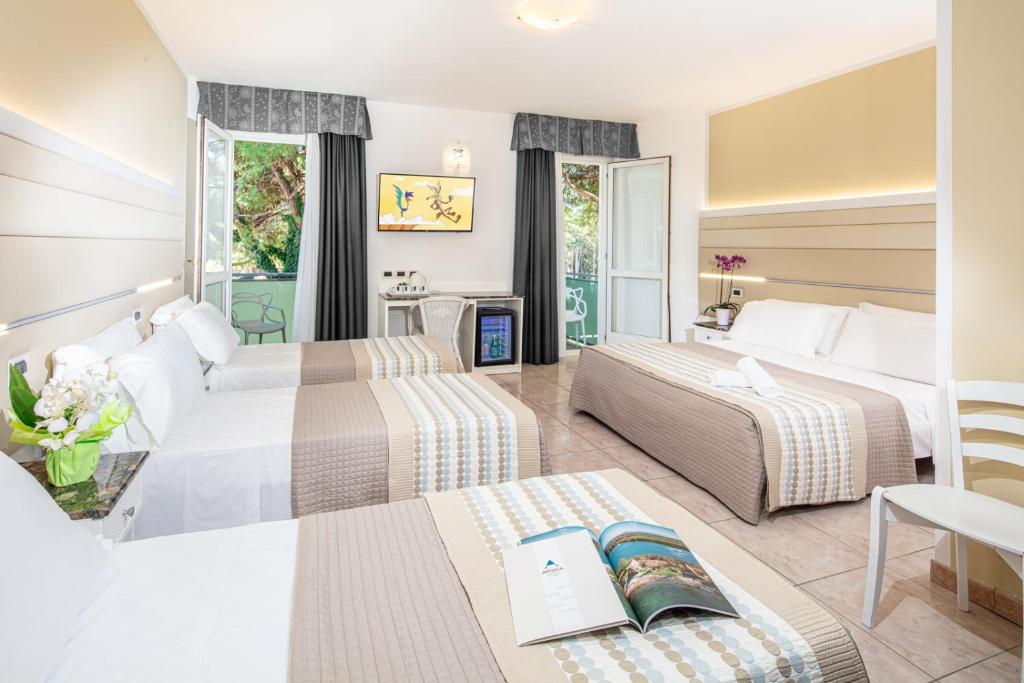 une chambre d'hôtel avec deux lits et un livre sur une table dans l'établissement Hotel Mediterraneo, à Lignano Sabbiadoro