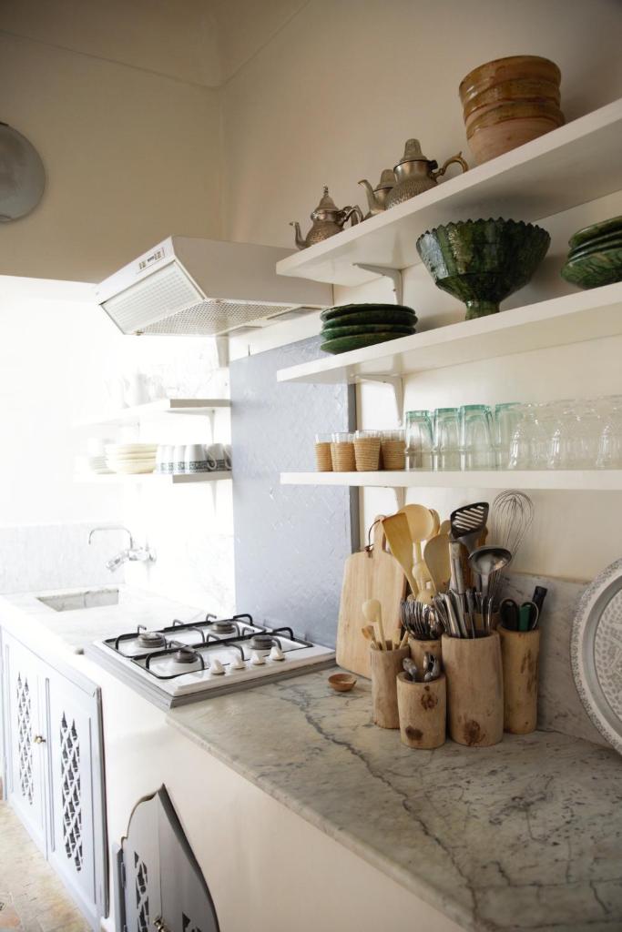 - une cuisine avec une cuisinière et des étagères avec des ustensiles dans l'établissement Riad Dar Wildeve, à Marrakech