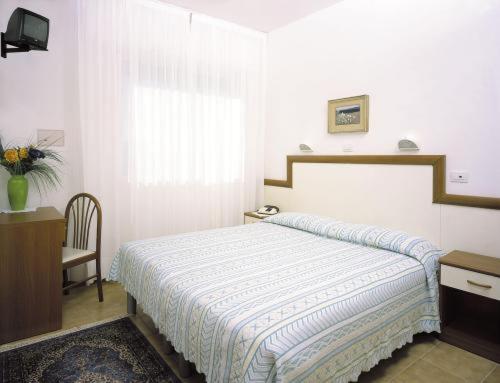 une chambre avec un lit, un bureau et une fenêtre dans l'établissement Hotel Bolivar, à Lido di Jesolo