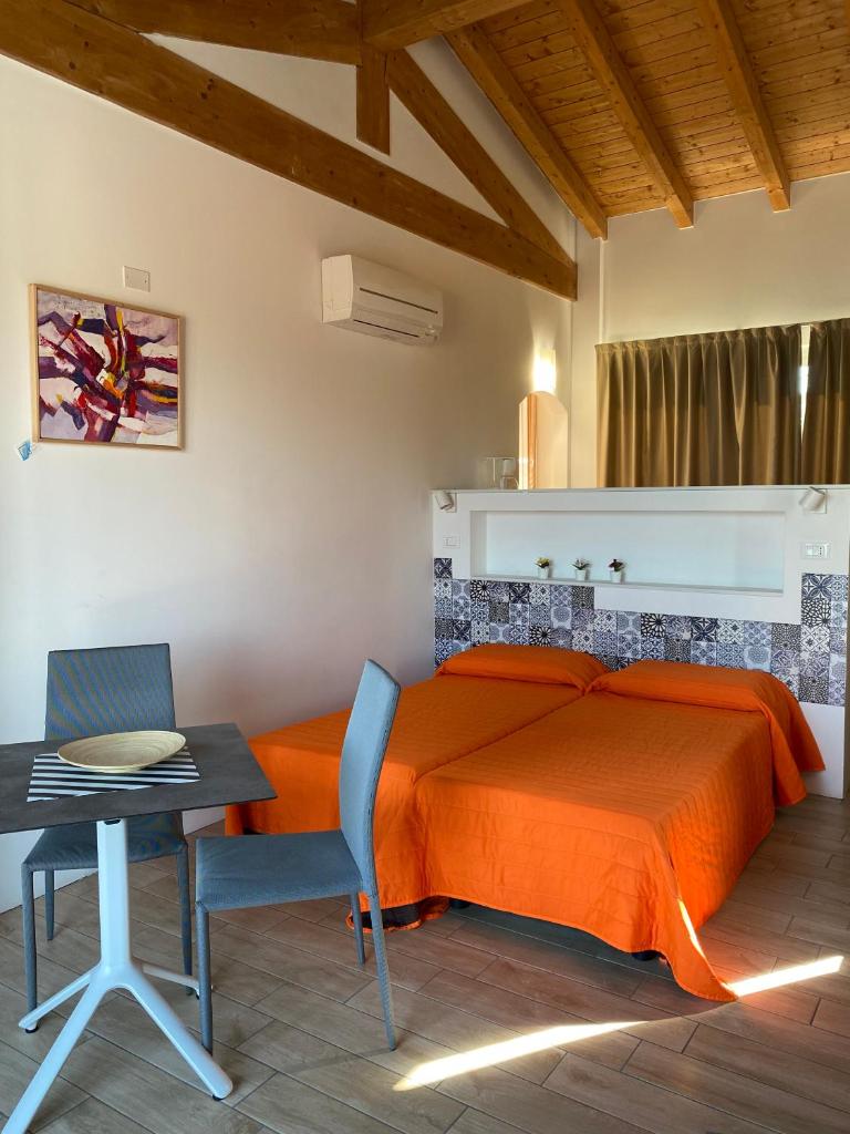 - une chambre avec un lit doté d'un couvre-lit orange et d'une table dans l'établissement Campeggio Villaggio San Giorgio Vacanze, à Manerba del Garda