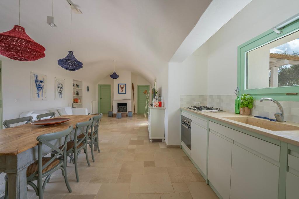 une cuisine avec une longue table et une cuisine avec des accents verts dans l'établissement Villa Eva, villa privata con piscina a sfioro, à Ostuni