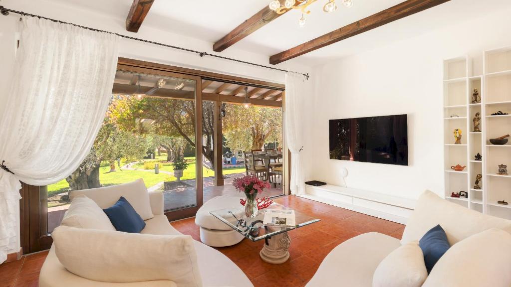 Il comprend un salon doté d'un mobilier blanc et d'une télévision. dans l'établissement VILLA CASTIGLIONE 9, Emma Villas, à Castiglione della Pescaia