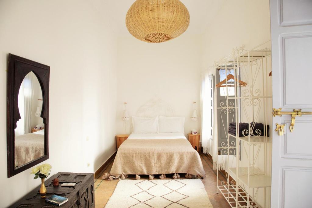 une chambre blanche avec un lit et un miroir dans l'établissement Riad Dar Wildeve, à Marrakech