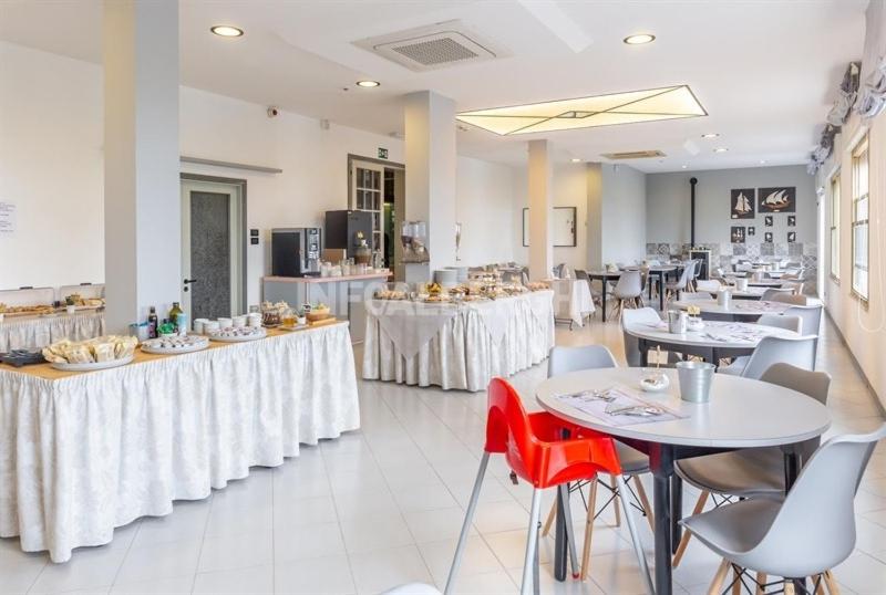 un restaurant avec des tables et des chaises blanches et un plan de travail dans l'établissement Albergo Aquila, à Rimini
