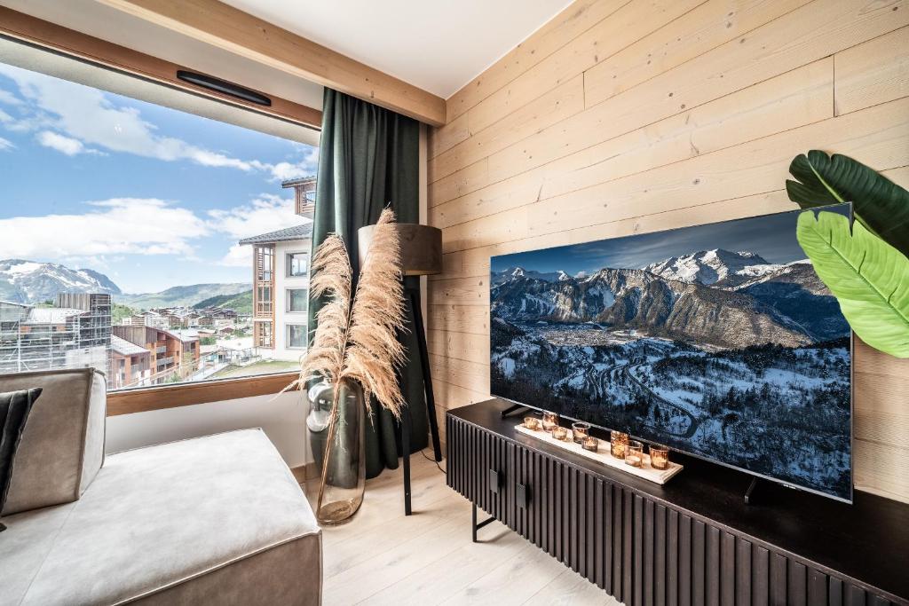 - un salon avec une grande télévision et une grande fenêtre dans l'établissement Apartment Tineo Alpe D'Huez - by EMERALD STAY, à L'Alpe-d'Huez