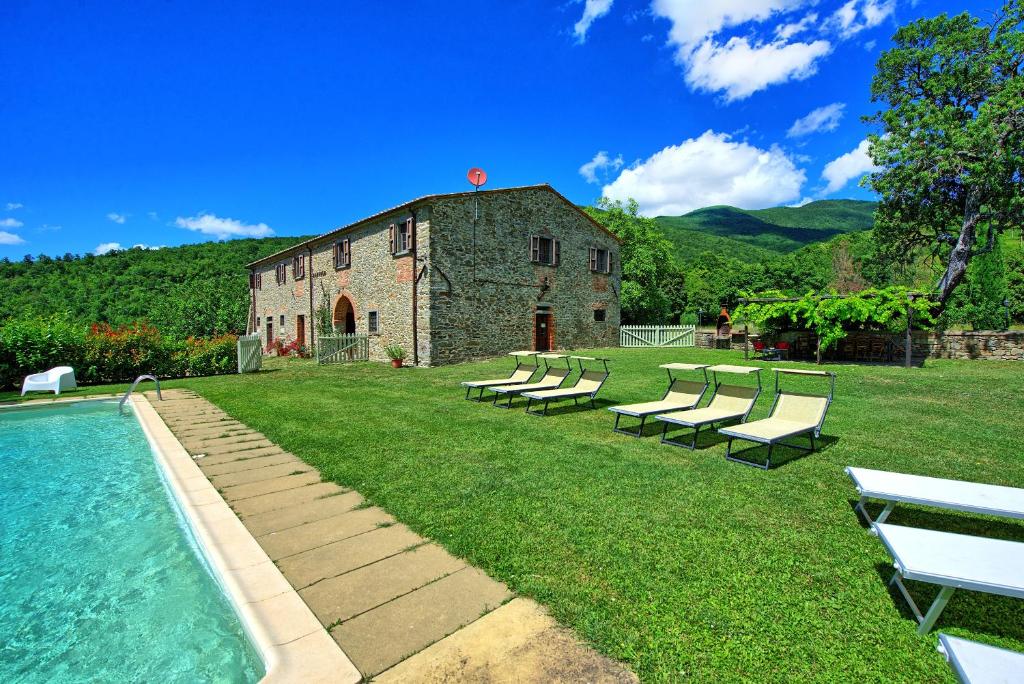 - un groupe de chaises et une piscine en face d'un bâtiment dans l'établissement Poggiolino by PosarelliVillas, à Chitignano