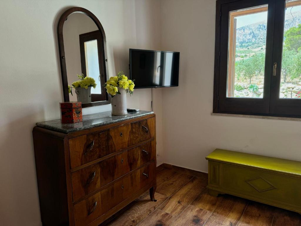 Cette chambre comprend une commode avec un miroir et une télévision. dans l'établissement Casale Nocellara, à Scopello