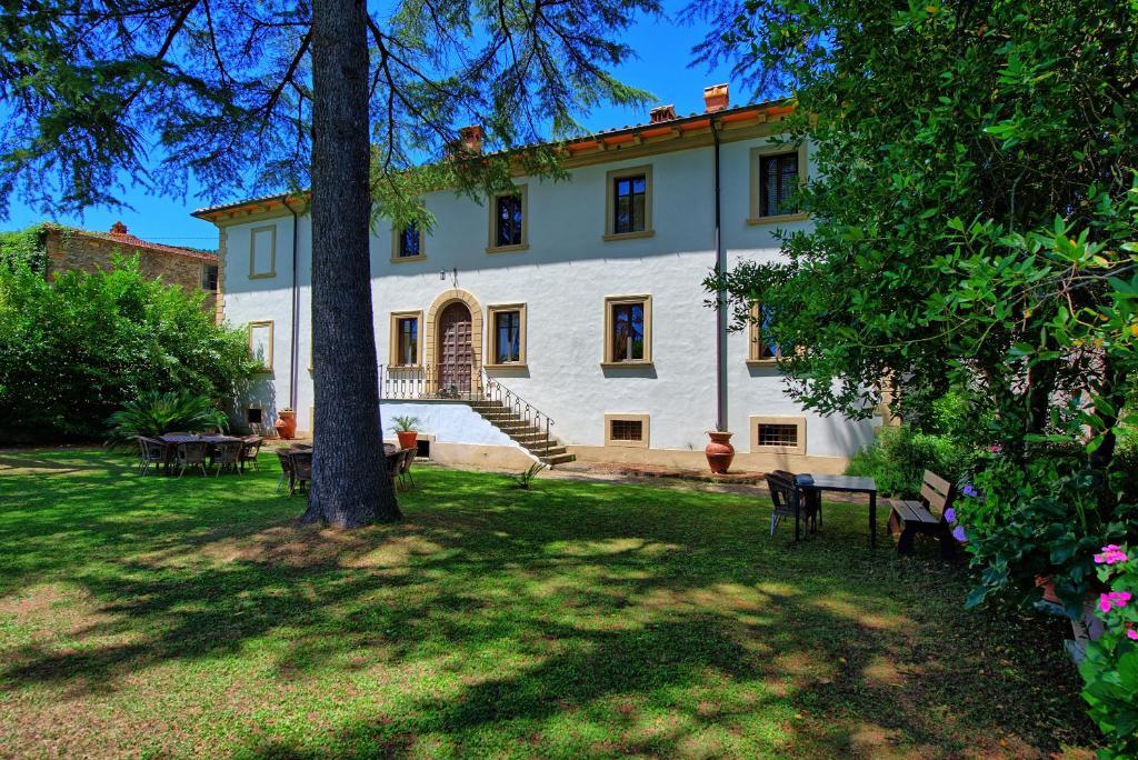 une grande maison blanche avec un arbre dans la cour dans l'établissement Villa Capolona by PosarelliVillas, à Calbenzano