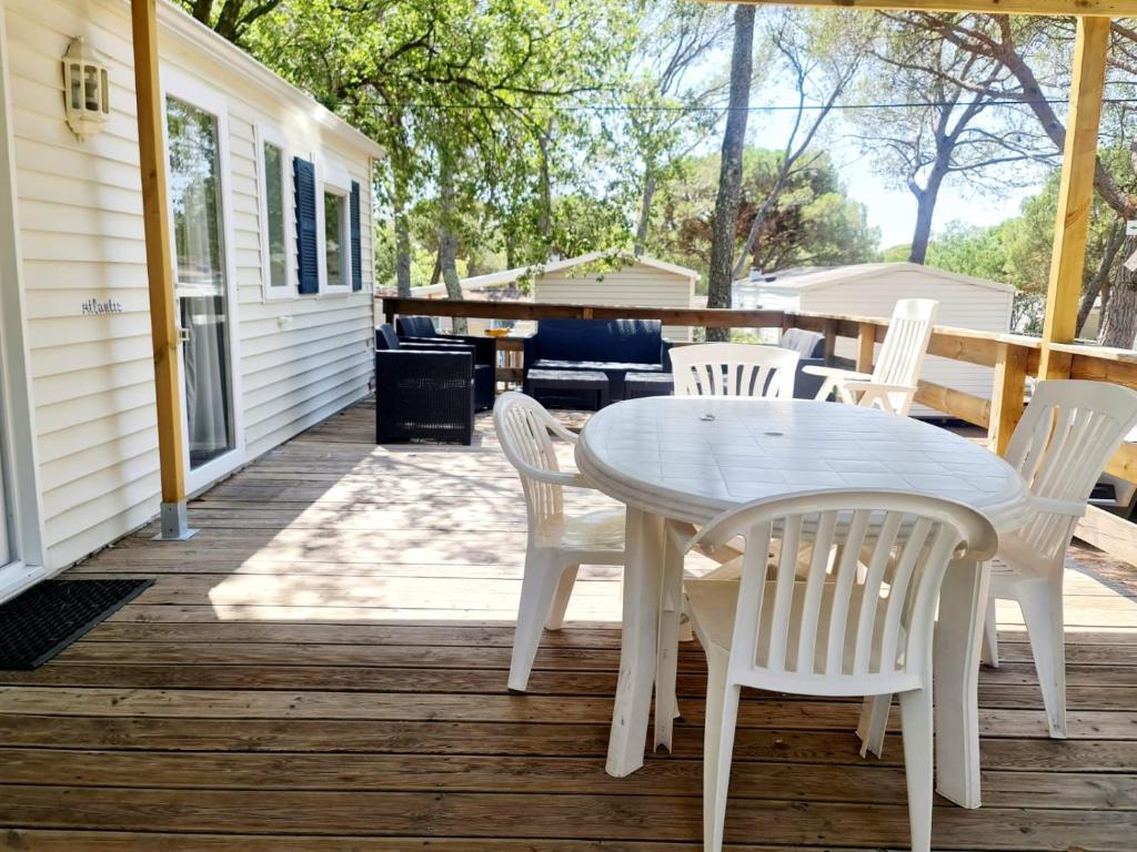 une table et des chaises blanches sur une terrasse en bois dans l'établissement La Baume La Palmeraie Camping Resort, à Fréjus