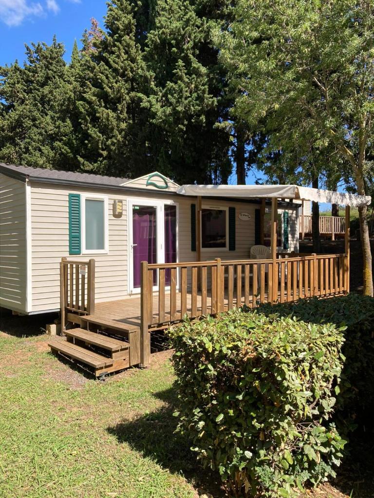 une petite maison avec un porche et une terrasse dans l'établissement camping paisible Marvilla park, à Agde