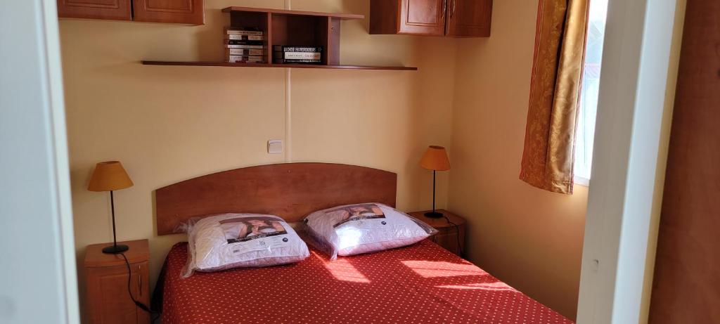 une chambre avec un lit avec deux oreillers dessus dans l'établissement Mobilhome "La Chaloupe" dans le Camping Saint Nicolas, au Bec-Hellouin 7 autres photos
