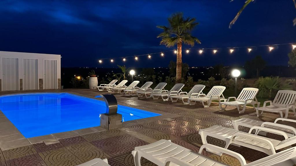 - un groupe de chaises et une piscine la nuit dans l'établissement Casa Vacanza Errante, à Menfi