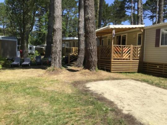 une cabane avec des arbres et une maison avec un porche dans l'établissement Mobilhome au bord de mer, à Piriac-sur-Mer