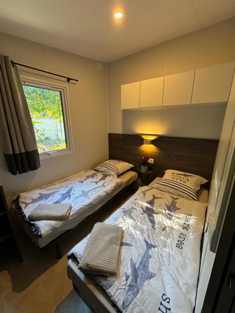deux lits assis dans une pièce avec une fenêtre dans l'établissement Bungalow vue mer, jacuzzi, terrase, jardin, à Saint-Raphaël