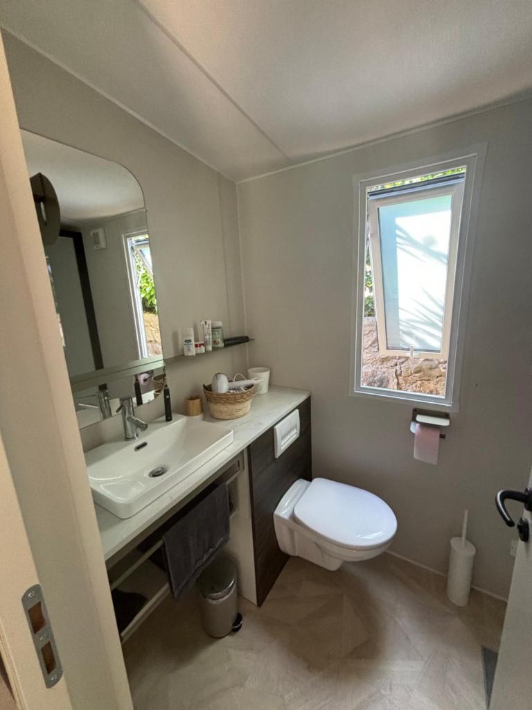 une salle de bain avec un lavabo et des toilettes et une fenêtre dans l'établissement Bungalow vue mer, jacuzzi, terrase, jardin, à Saint-Raphaël