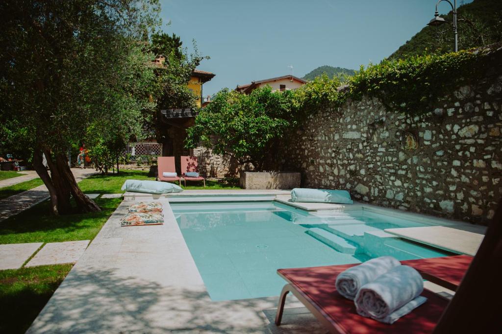 - une piscine dans une cour à côté d'un mur en pierre dans l'établissement Villa Frida, à Salò