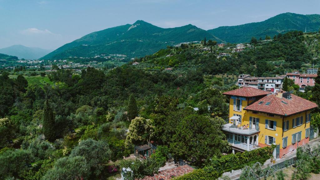 une maison jaune sur une colline avec des montagnes en arrière-plan dans l'établissement Villa Frida, à Salò