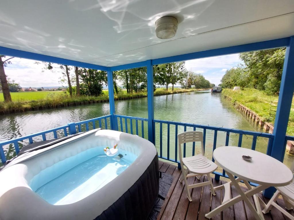 une baignoire assise sur une terrasse à côté d'une rivière dans l'établissement Cottage flottant Terrasse Nature près Dijon, à Ouges